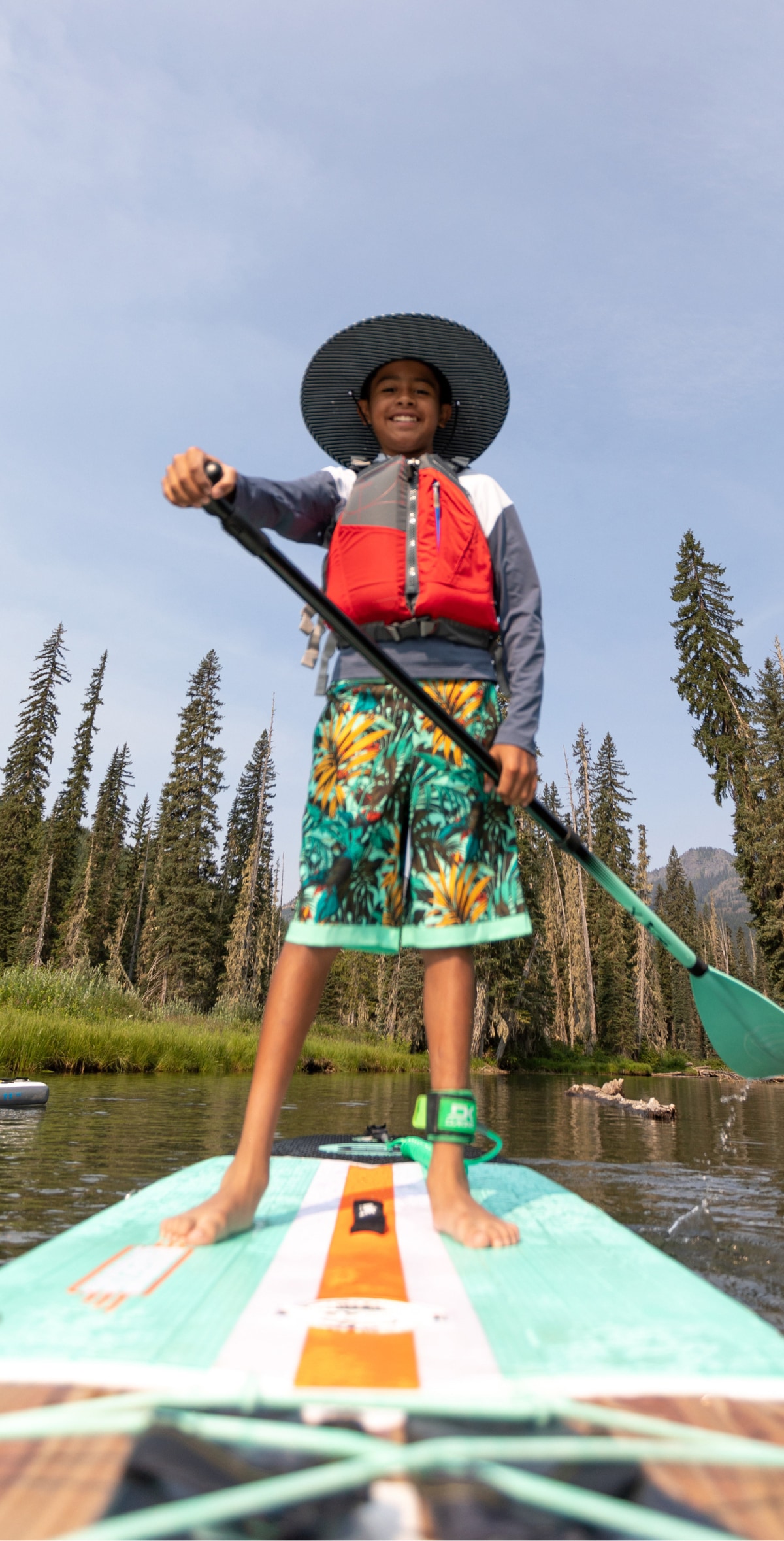 A person stands on a paddle board and smiles for the camera.