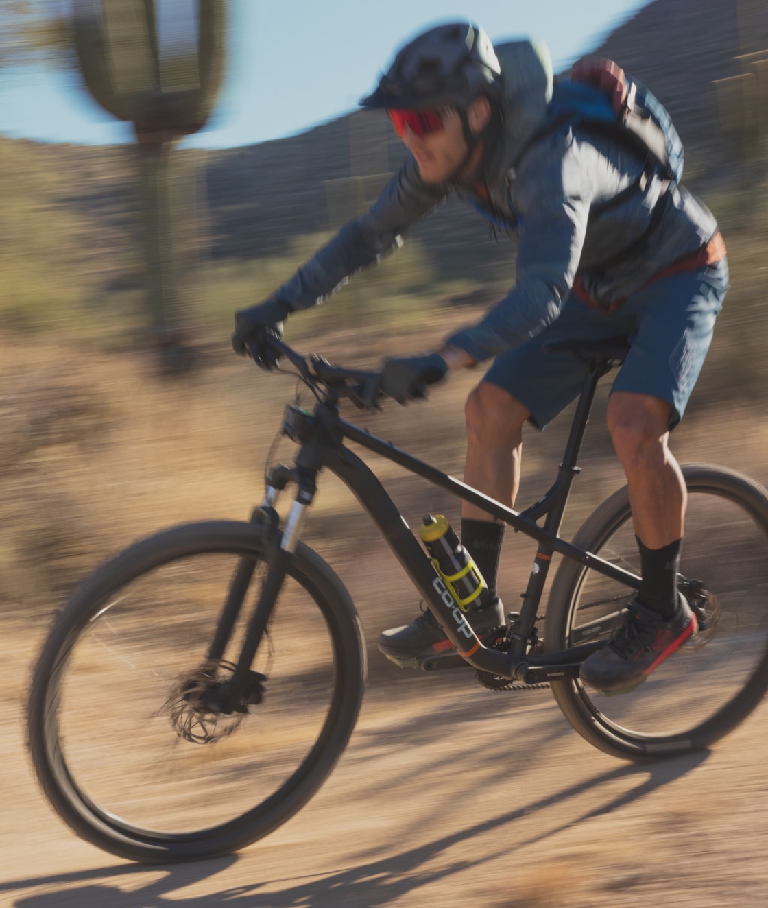 A person speeds through a dirt trail on their Co-op Cycles bike.