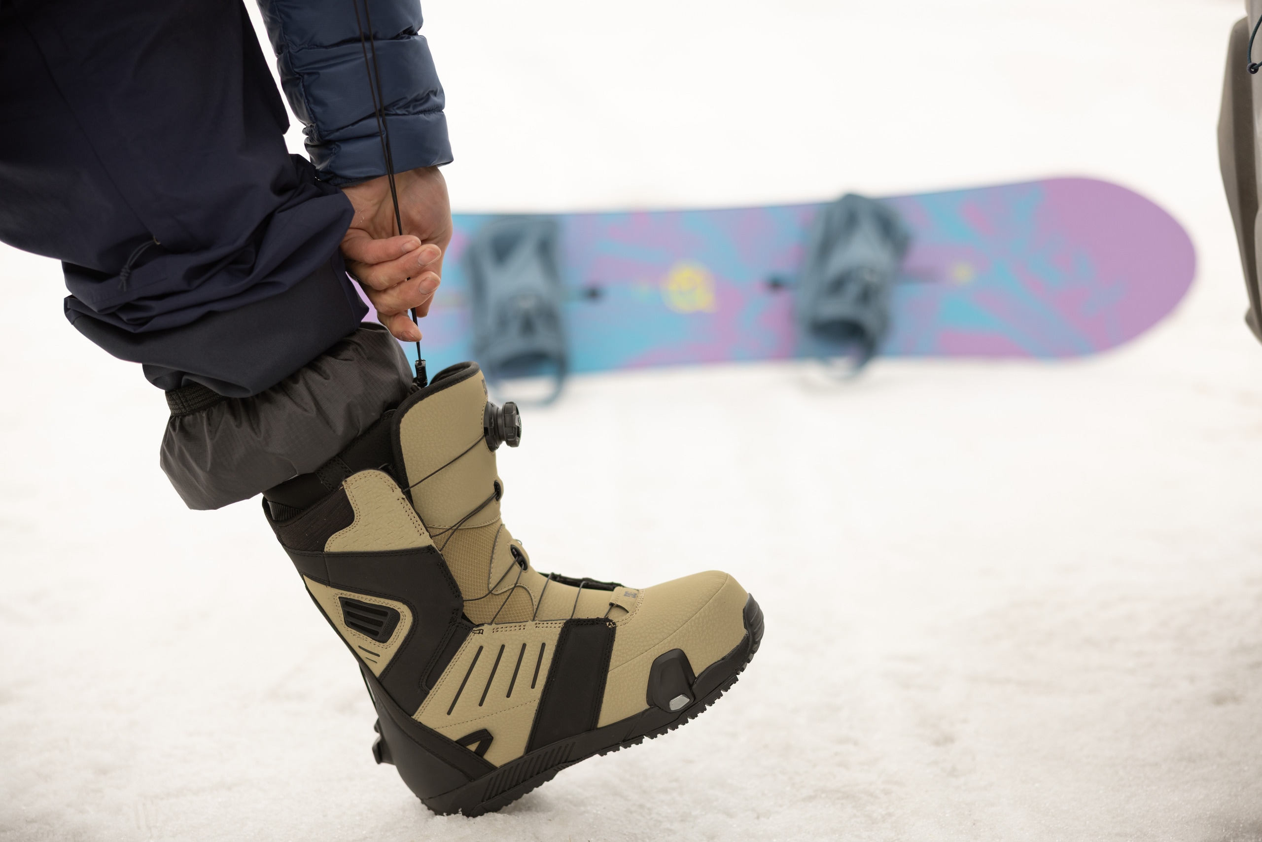 A snowboarder puts on a snowboard boots