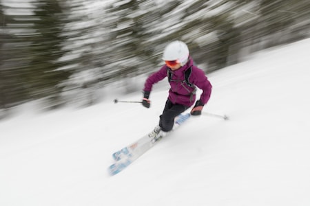 A skier in a purple jacket traverses down a slope.