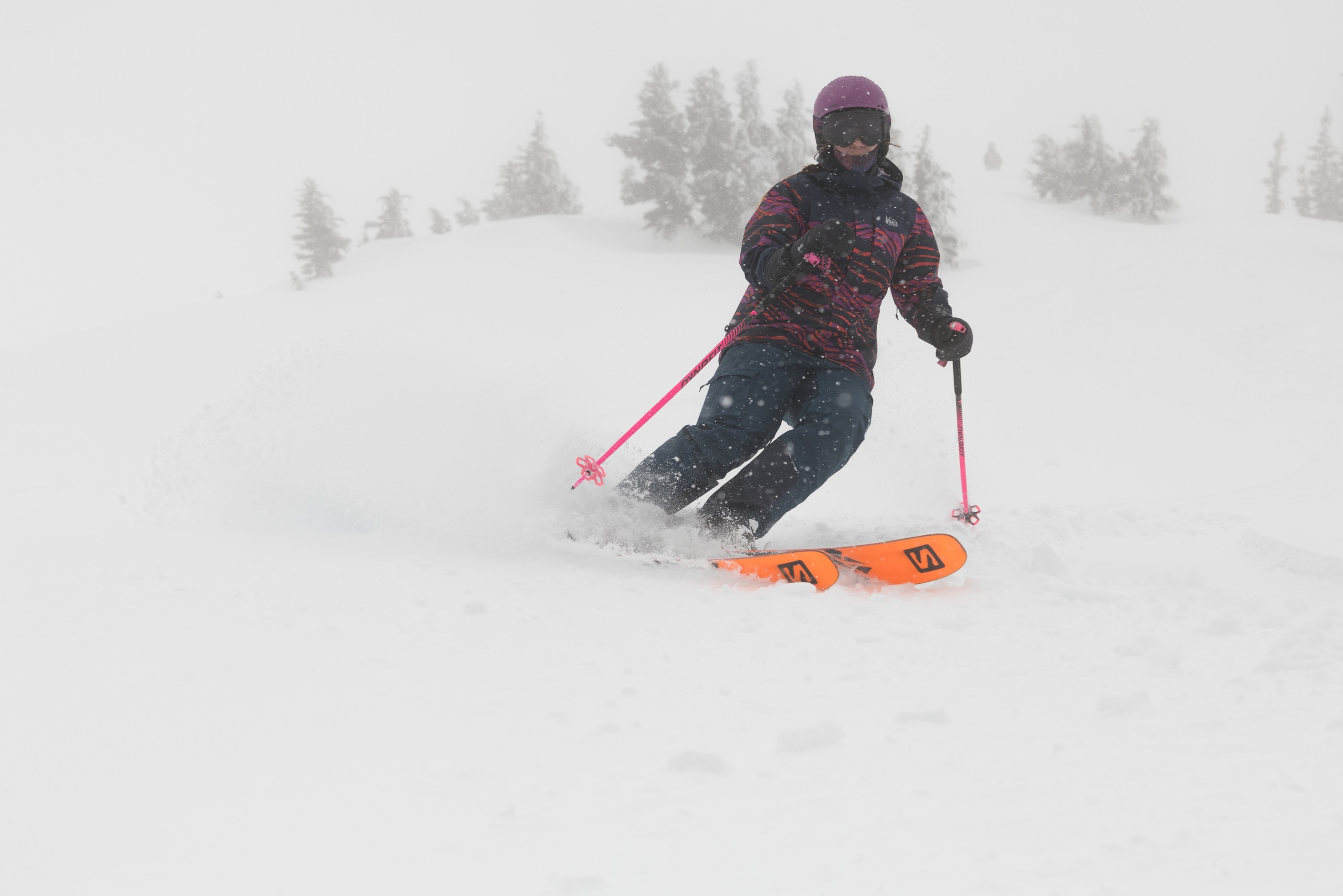 A skier plants her ski poles on the slope