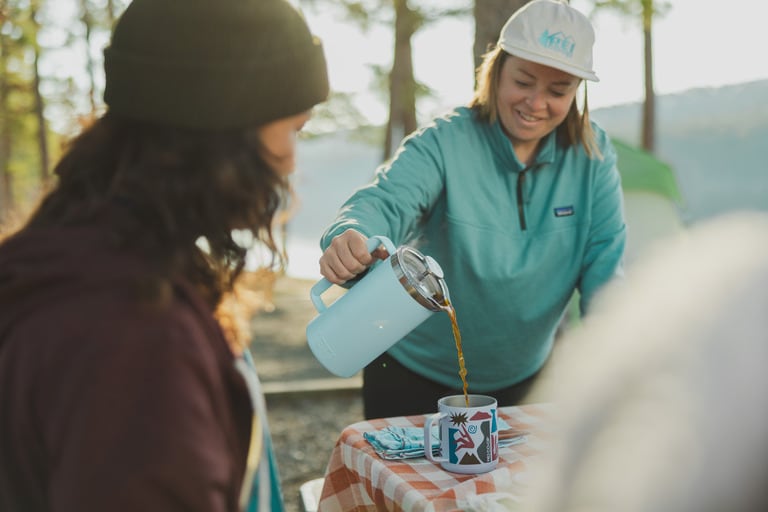 Picture of a camper pouring coffee from a French press.