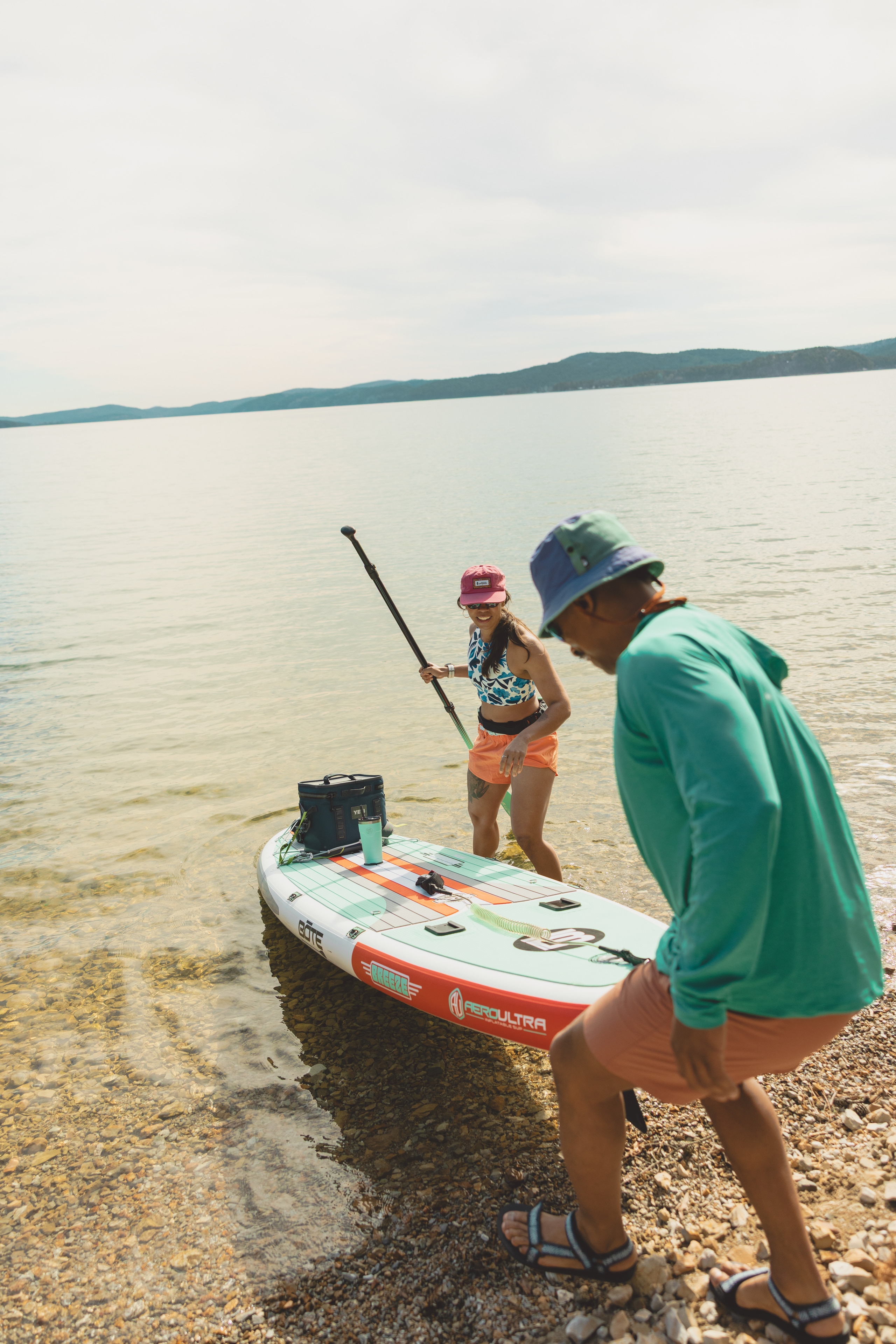 two people launch their paddle board into the water