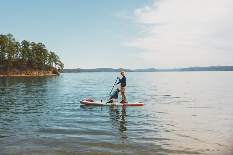 A person paddles with his dog on the water.
