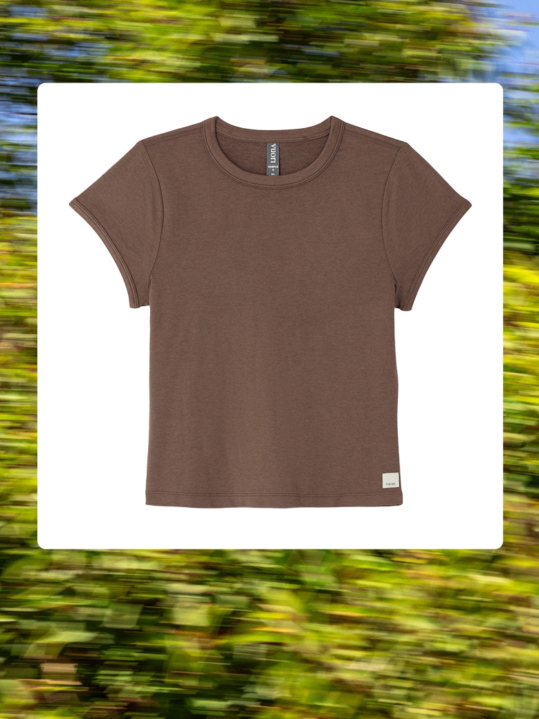 The Halo Baby T-Shirt from Vuori over an image of trees.