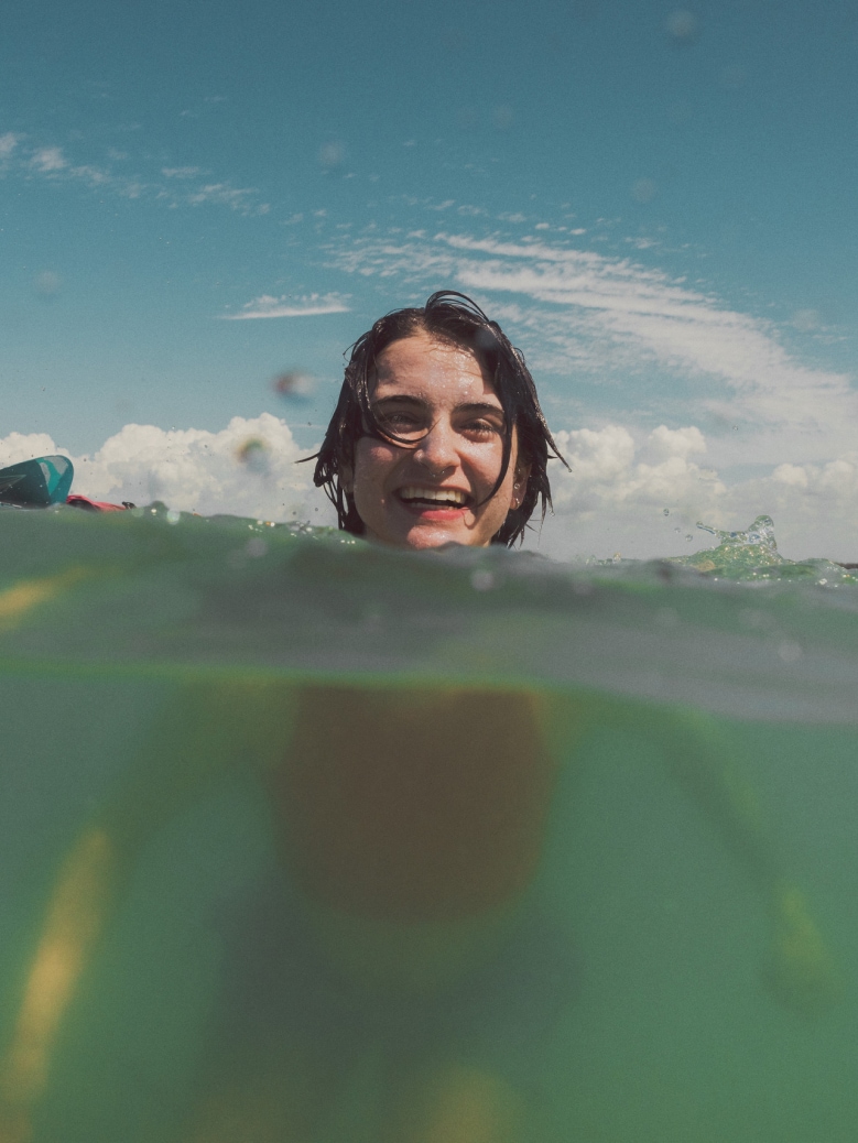 A person smiles for the camera while swimming.