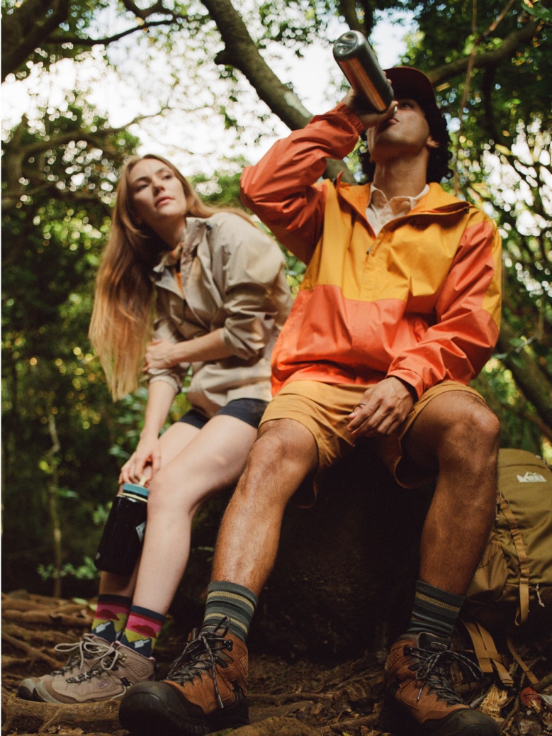 Two people sit down to take a break & drink from their water bottles.