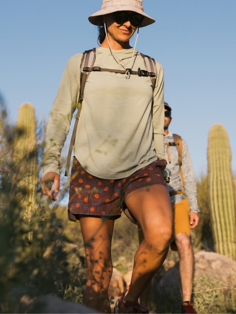 Two people hike through a desert trail on a sunny day.