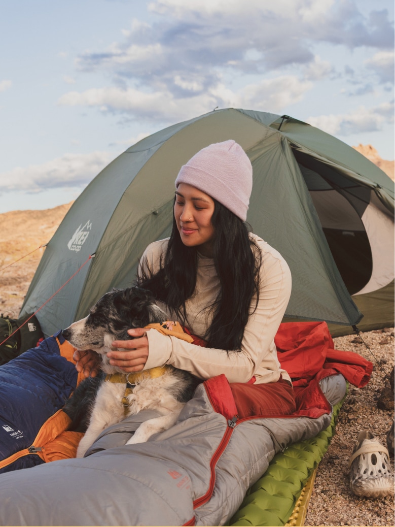 A person and their dog take time to relax in their co-op brand sleeping bag.