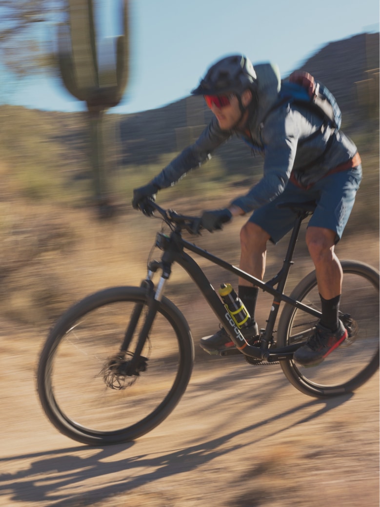 A person speeds through a desert trail on their bike.
