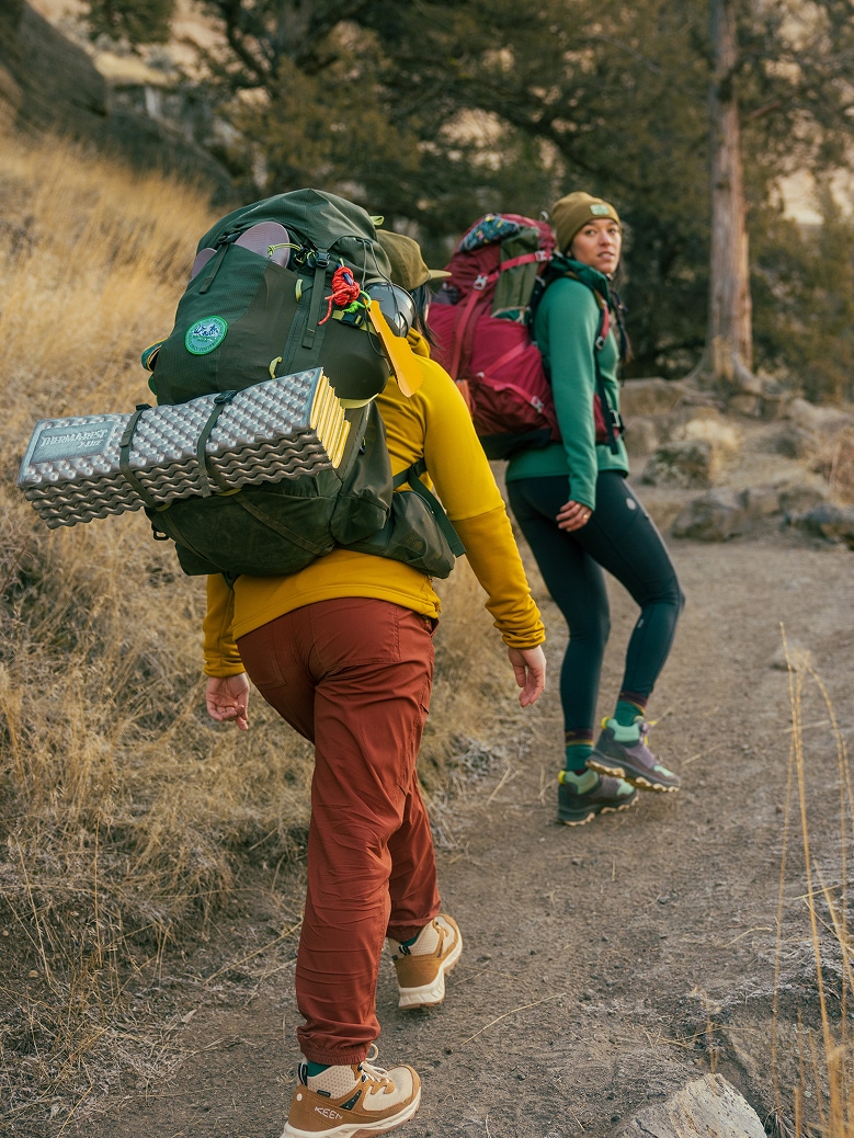 Two backpackers hike up a trail.