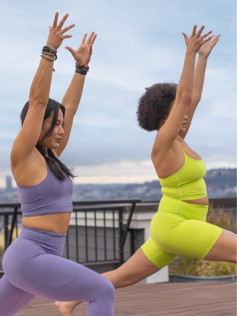 Two people do yoga outdoors.