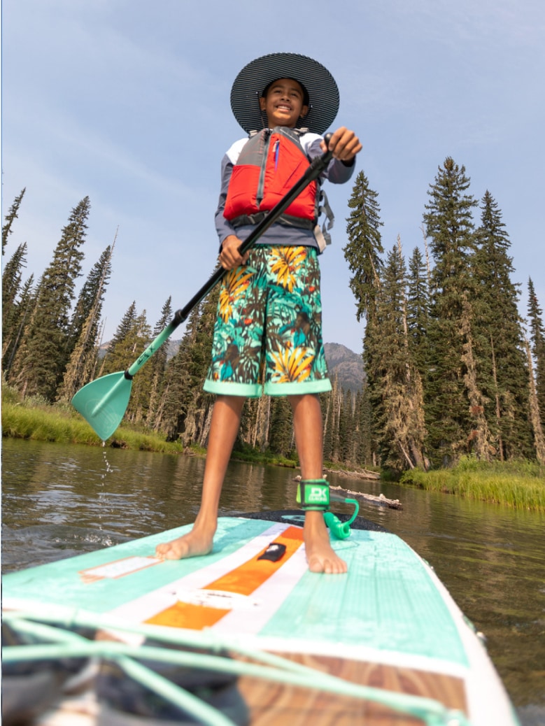 A person smiles for the camera while standing on their paddle board.