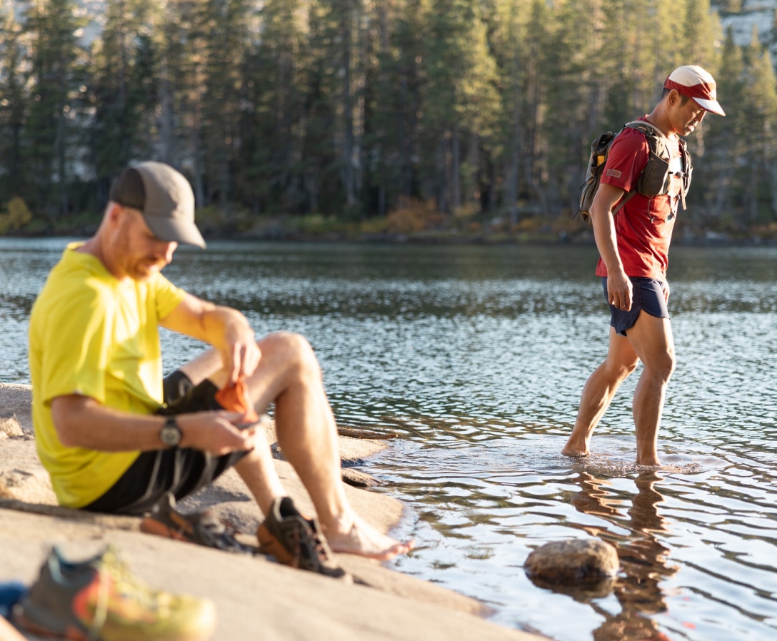 Two people enjoy dipping their feet into a lake.