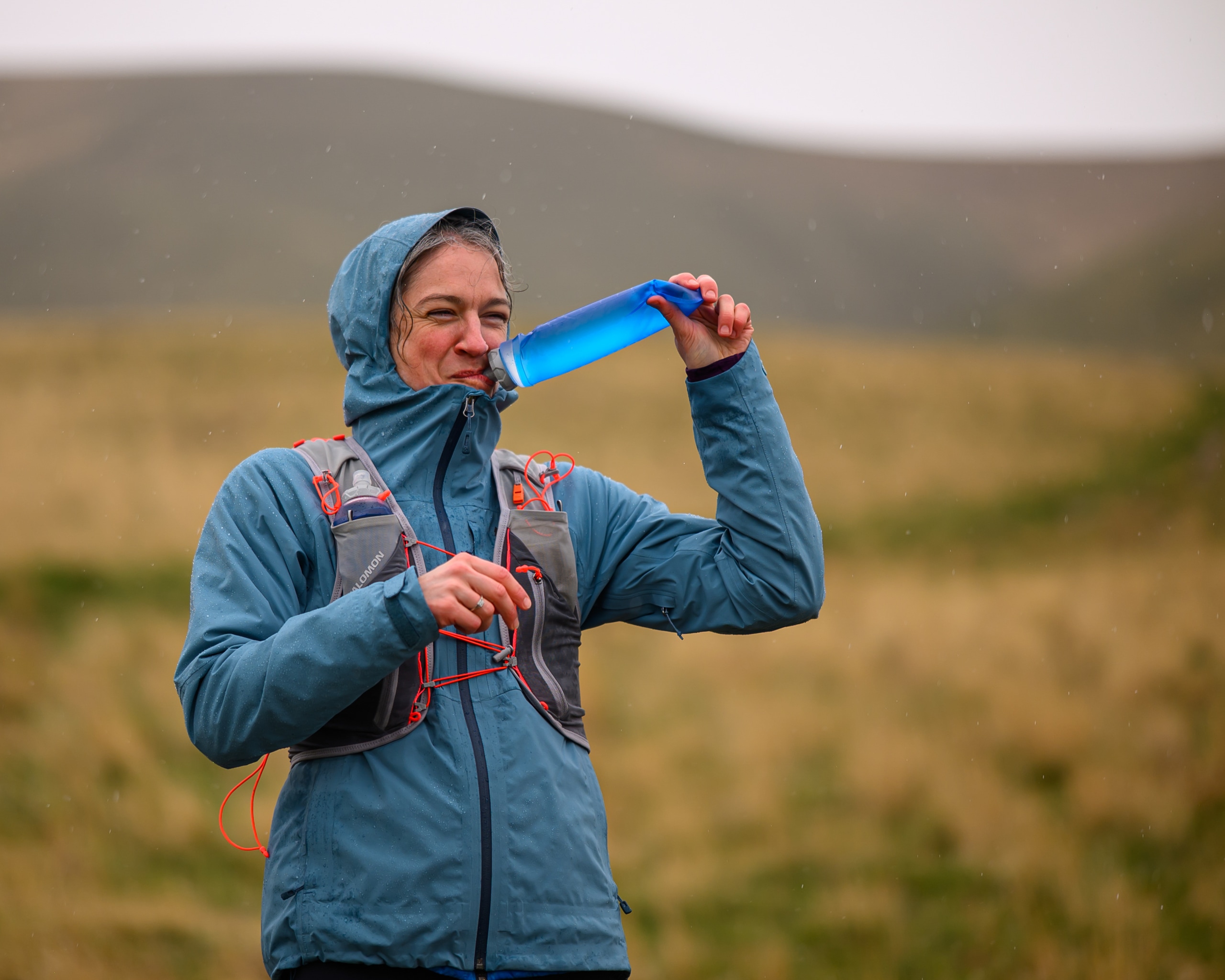 A runner in the Salomon Adv Skin 12 hydration vest, sipping water from a soft flask