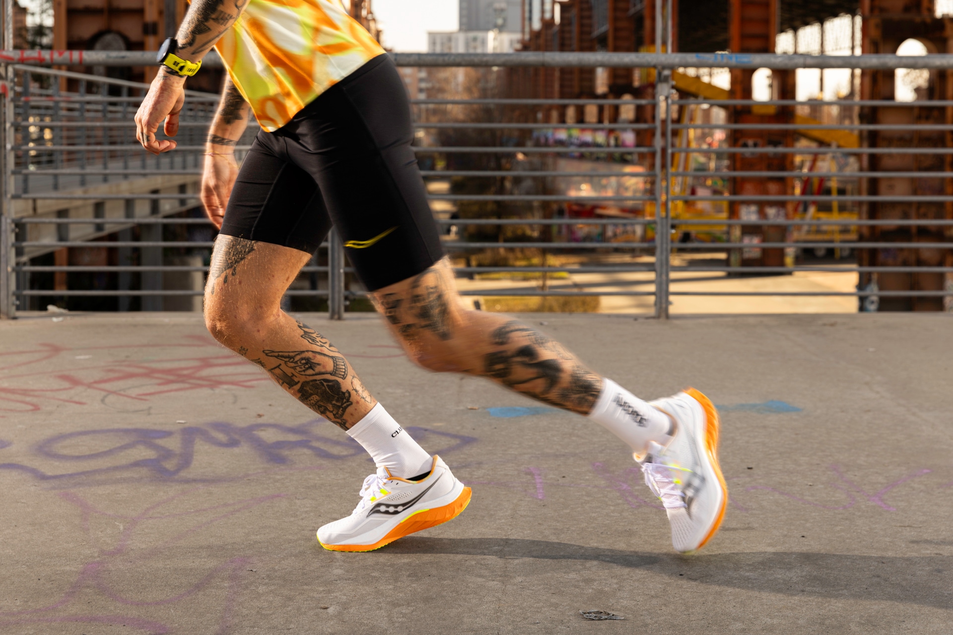 A person with tattooed legs running in the Saucony Endorphin Speed 4 road-running shoes