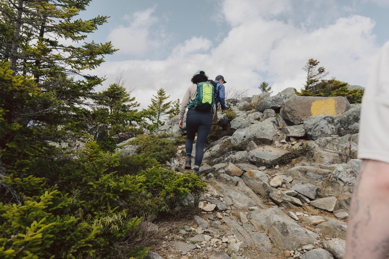 Three people hike up a rocky steep trail.
