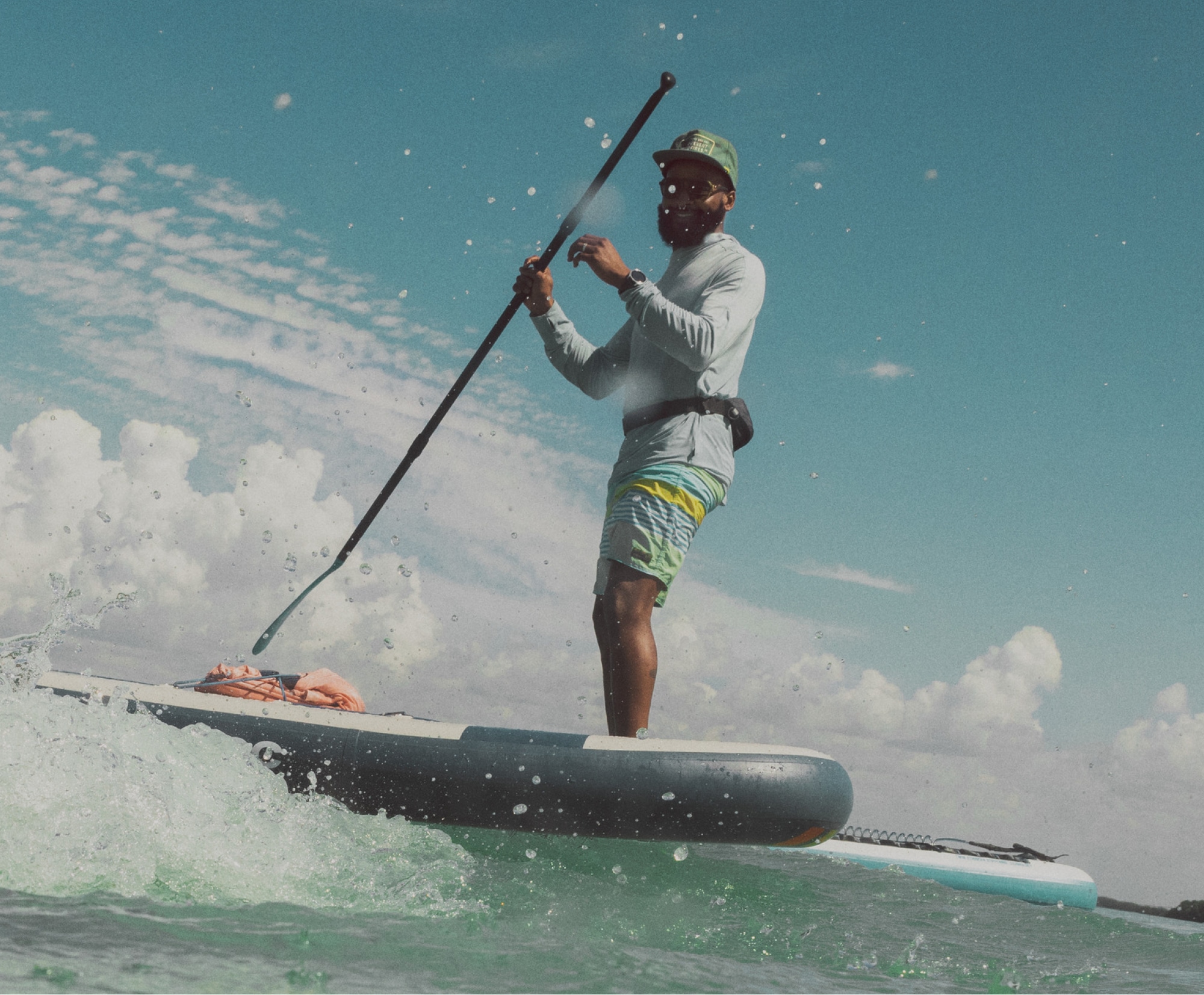 A person laughs on their paddle board. 