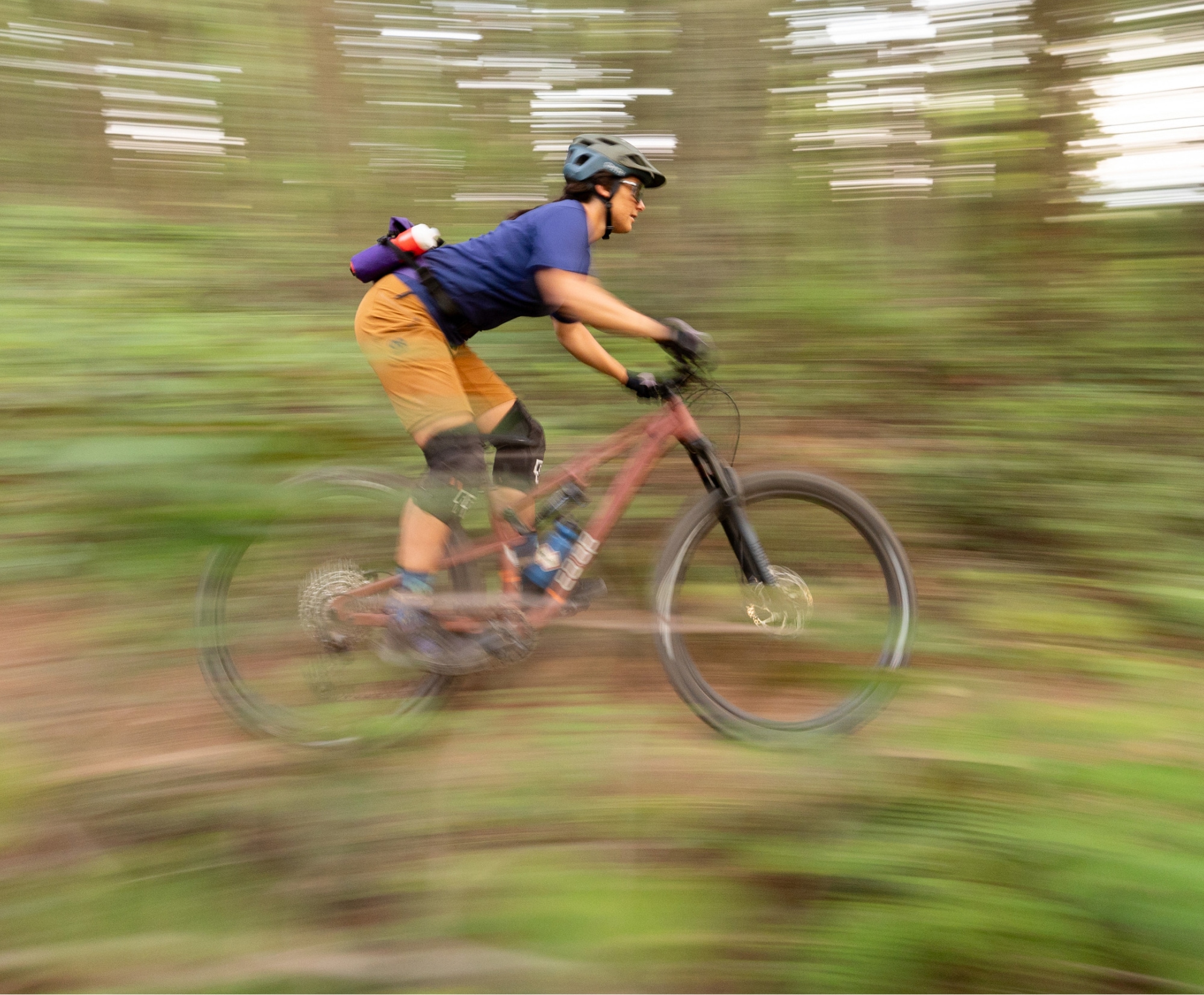 A person rides their bike through a trail in a forest.