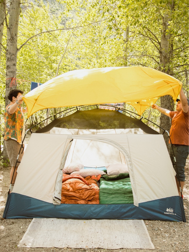Two people putting the rainfly on their R E I Co-op Campwell tent.