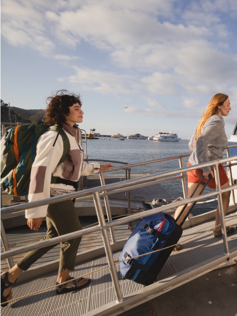 Travelers board a boat with their luggage.
