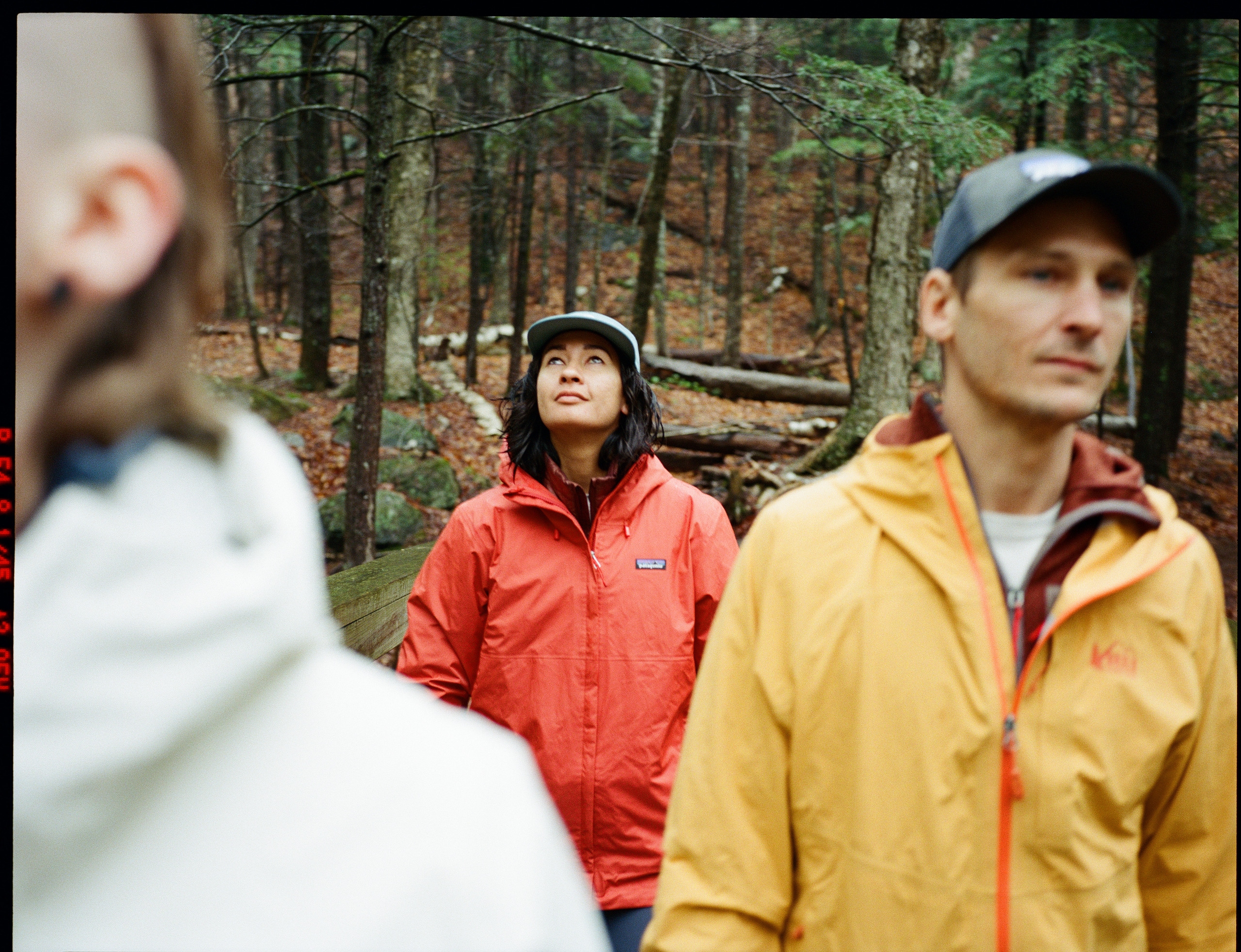 Three hikers wear colorful rain jackets 