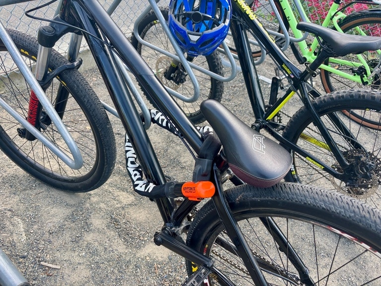 A black bike is locked to the bike rack with a Kryptonite chain lock