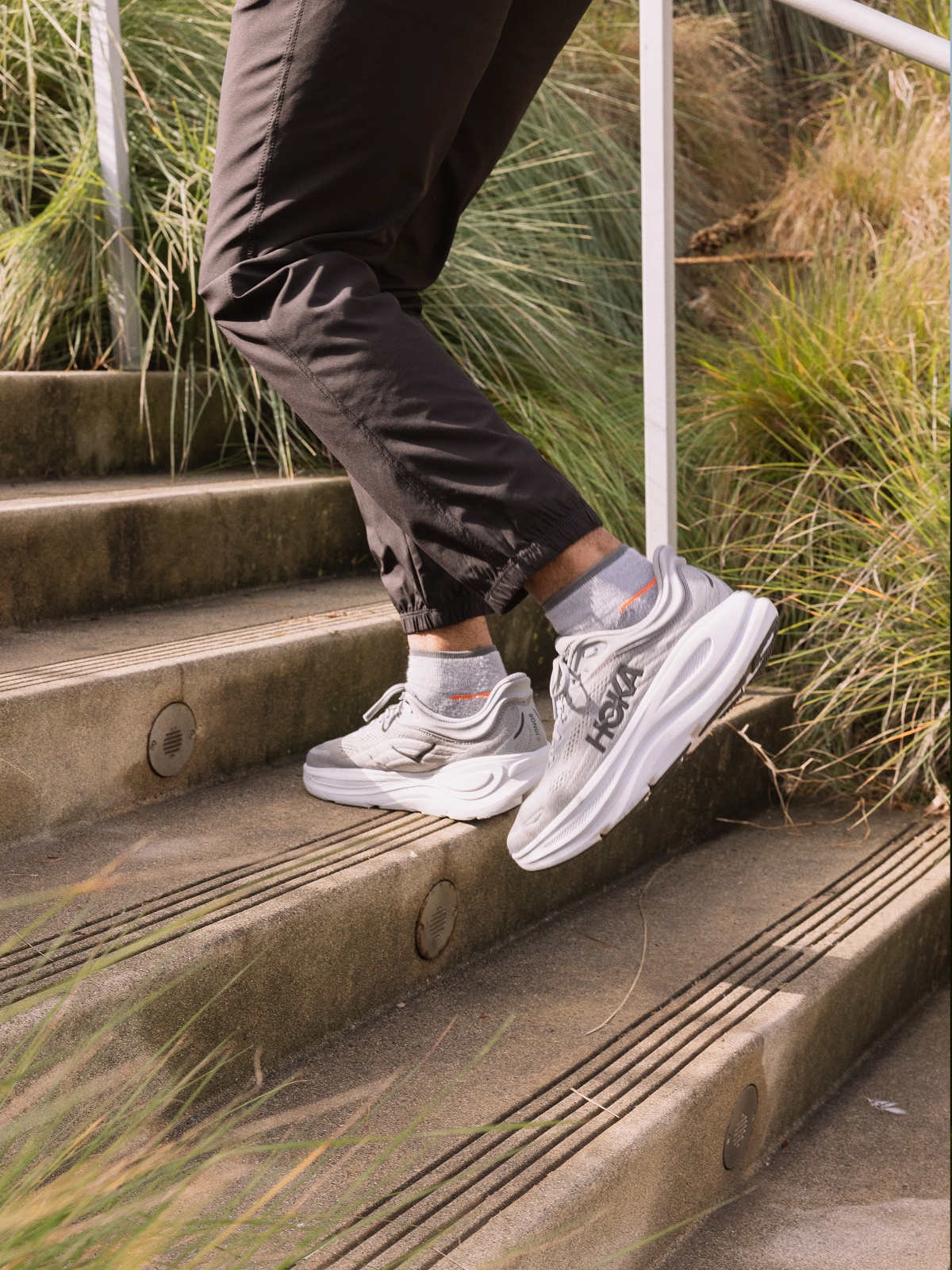 A person jogs up a staircase in their HOKA shoes.