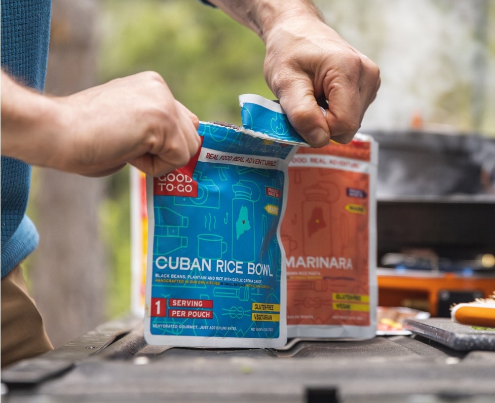 A person opens up a pouch of backpacking food.