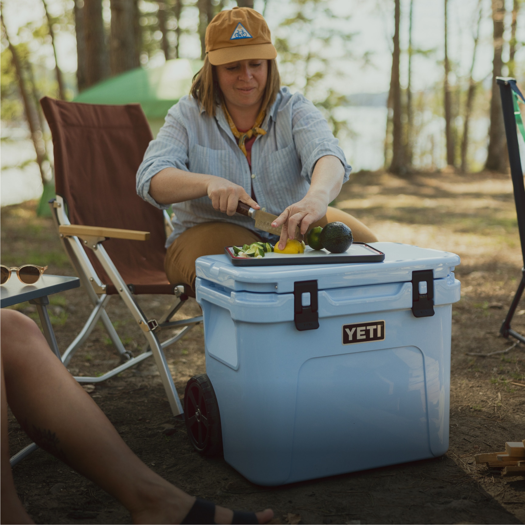A person slices a lemon on a cutting board on top of their YETI cooler.