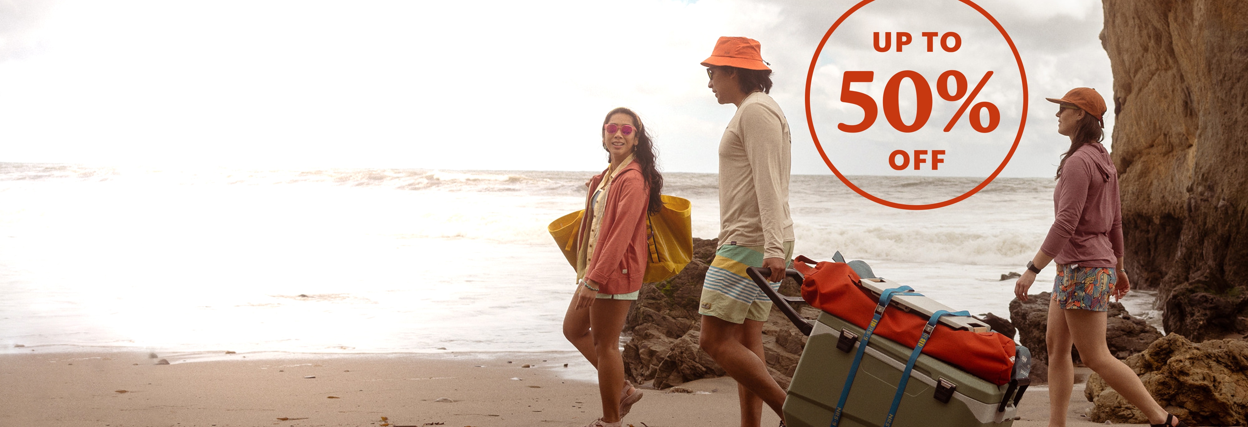 Up to 50% off. A group of people walk down to the beach with their gear.