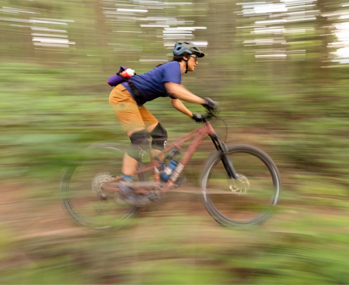 A person zooms through a forest trail on their bike.