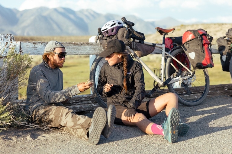 Two cyclists sitting down on the road next to their bikes