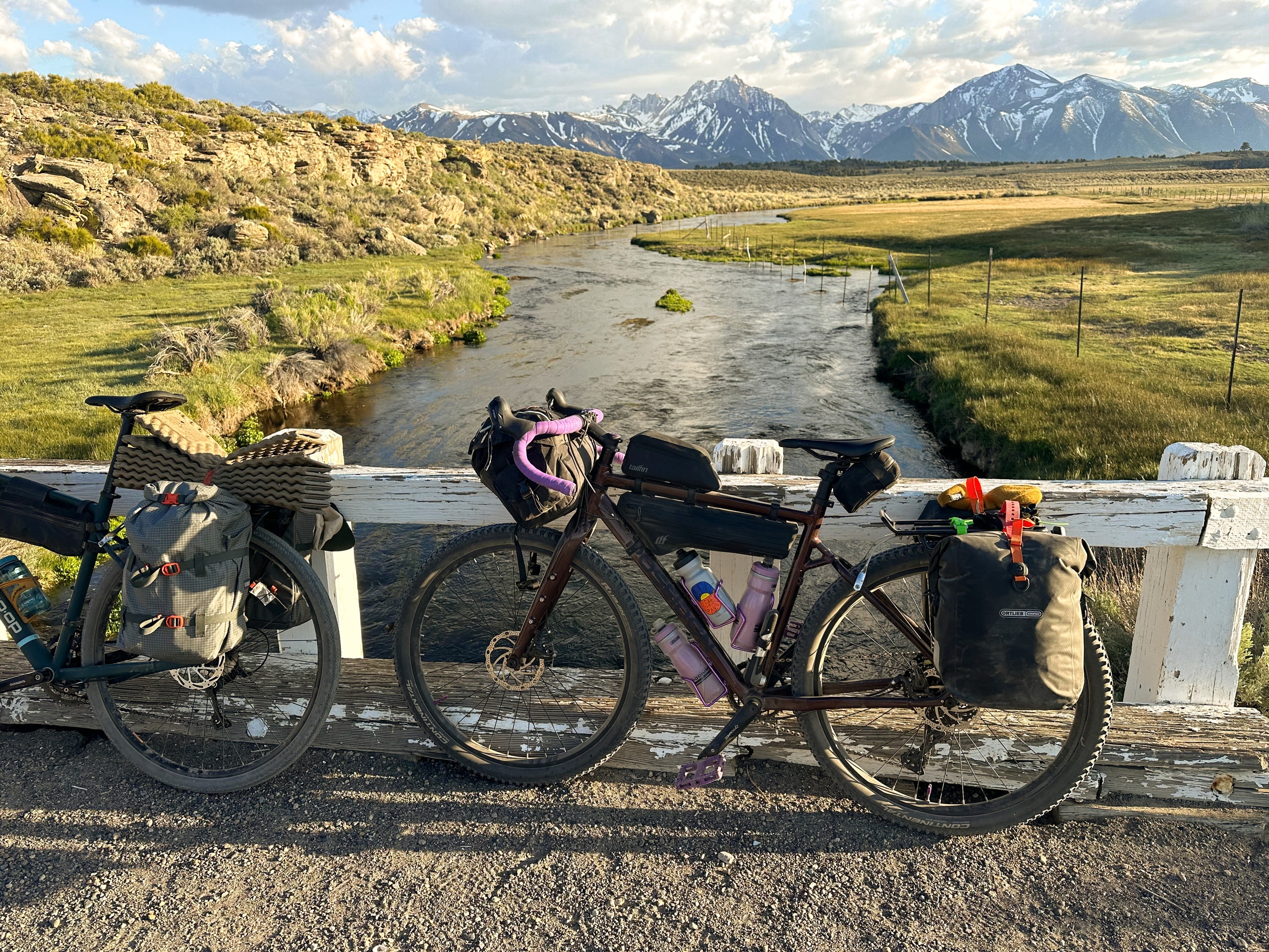 Two bikes on a bridge over a stream