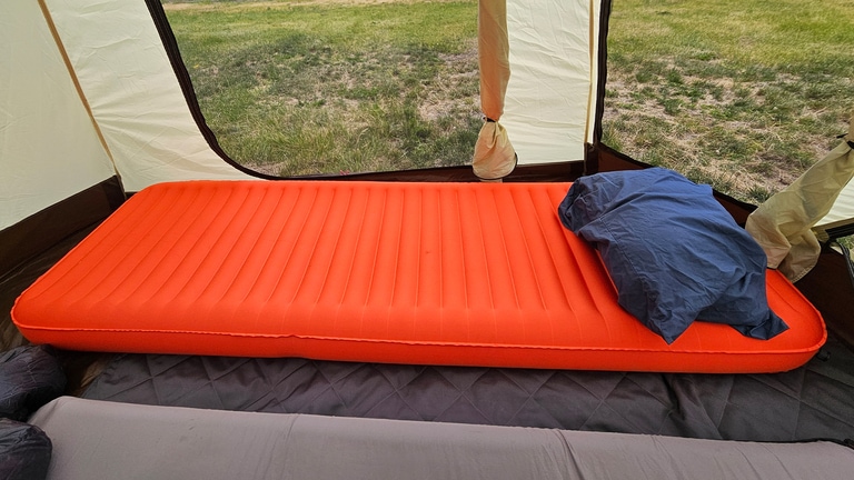 Picture of an orange-red sleeping pad inside a tent
