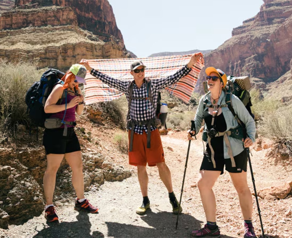 Three people laugh and smile while on a hike.