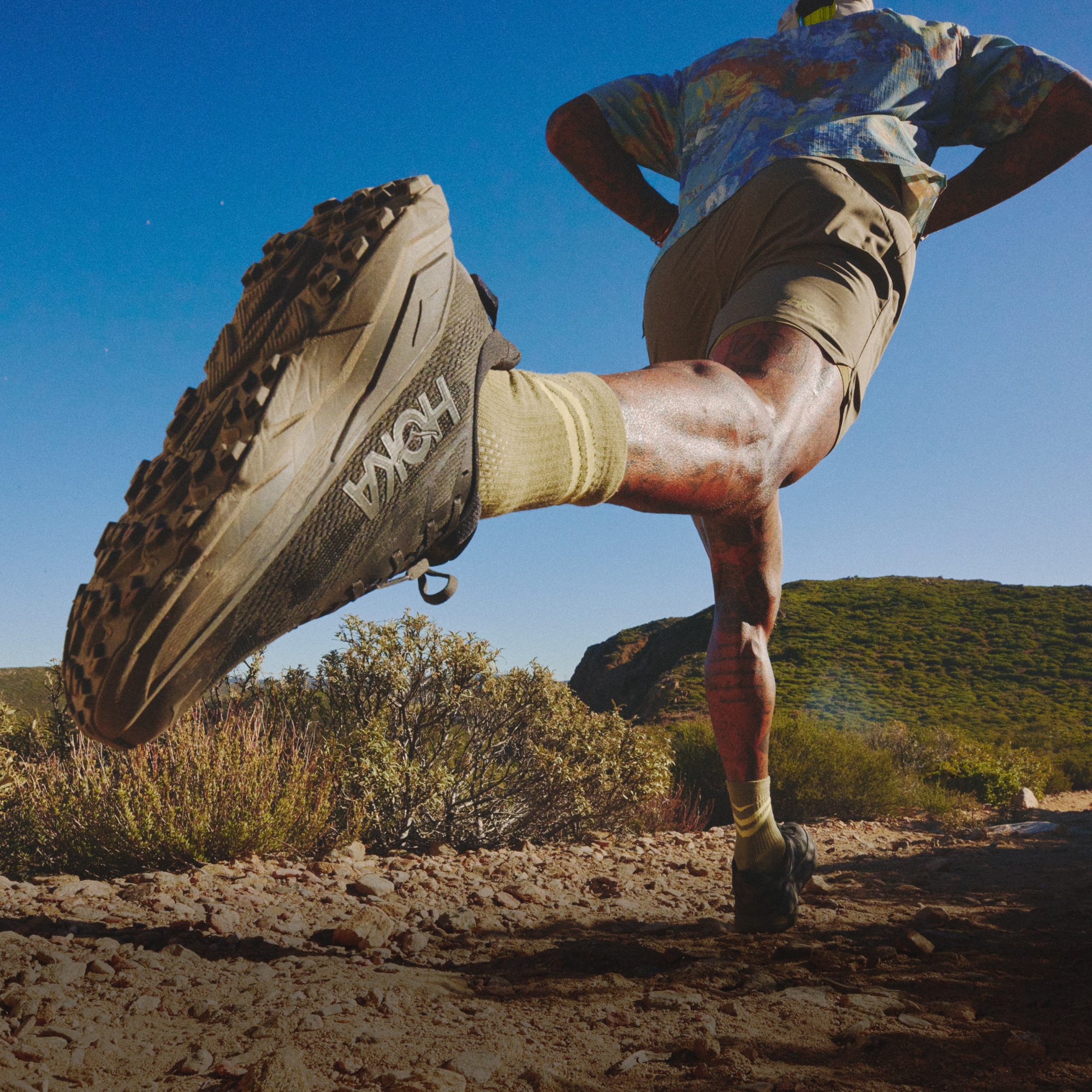 A person runs through a dirt trail on a sunny day.