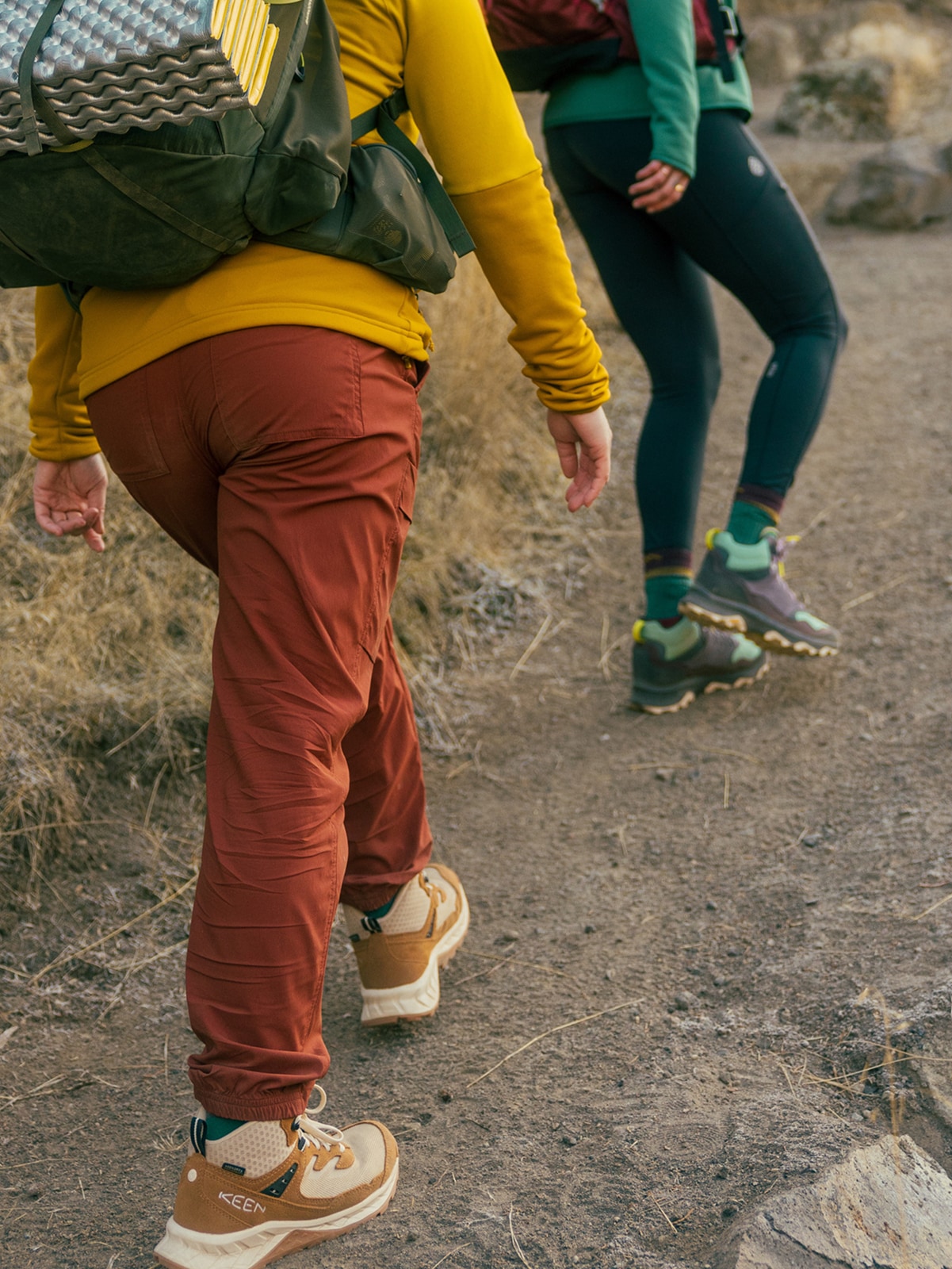 Two people hike up a dirt trail.