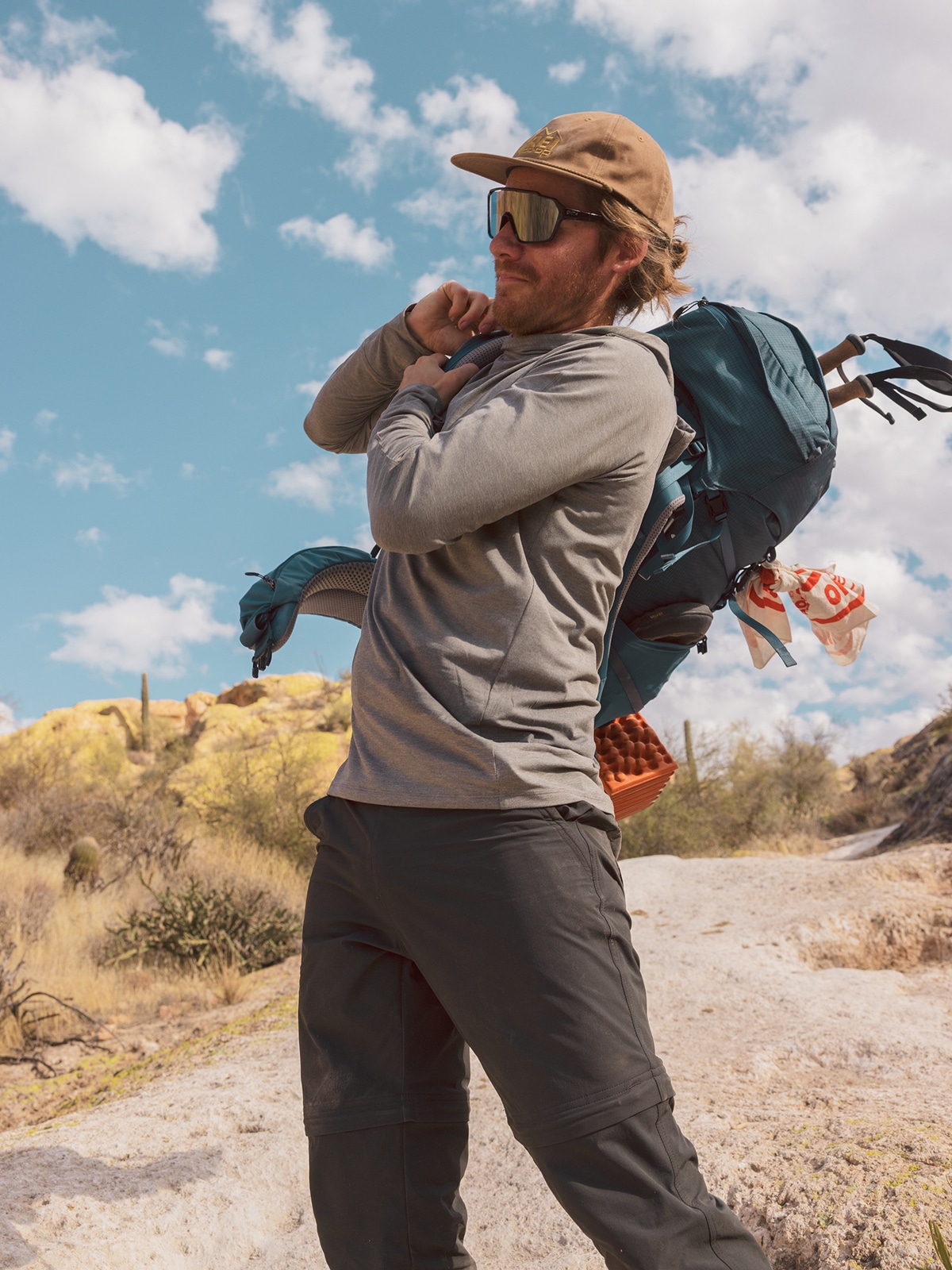 A person pulls on their pack during a hike.