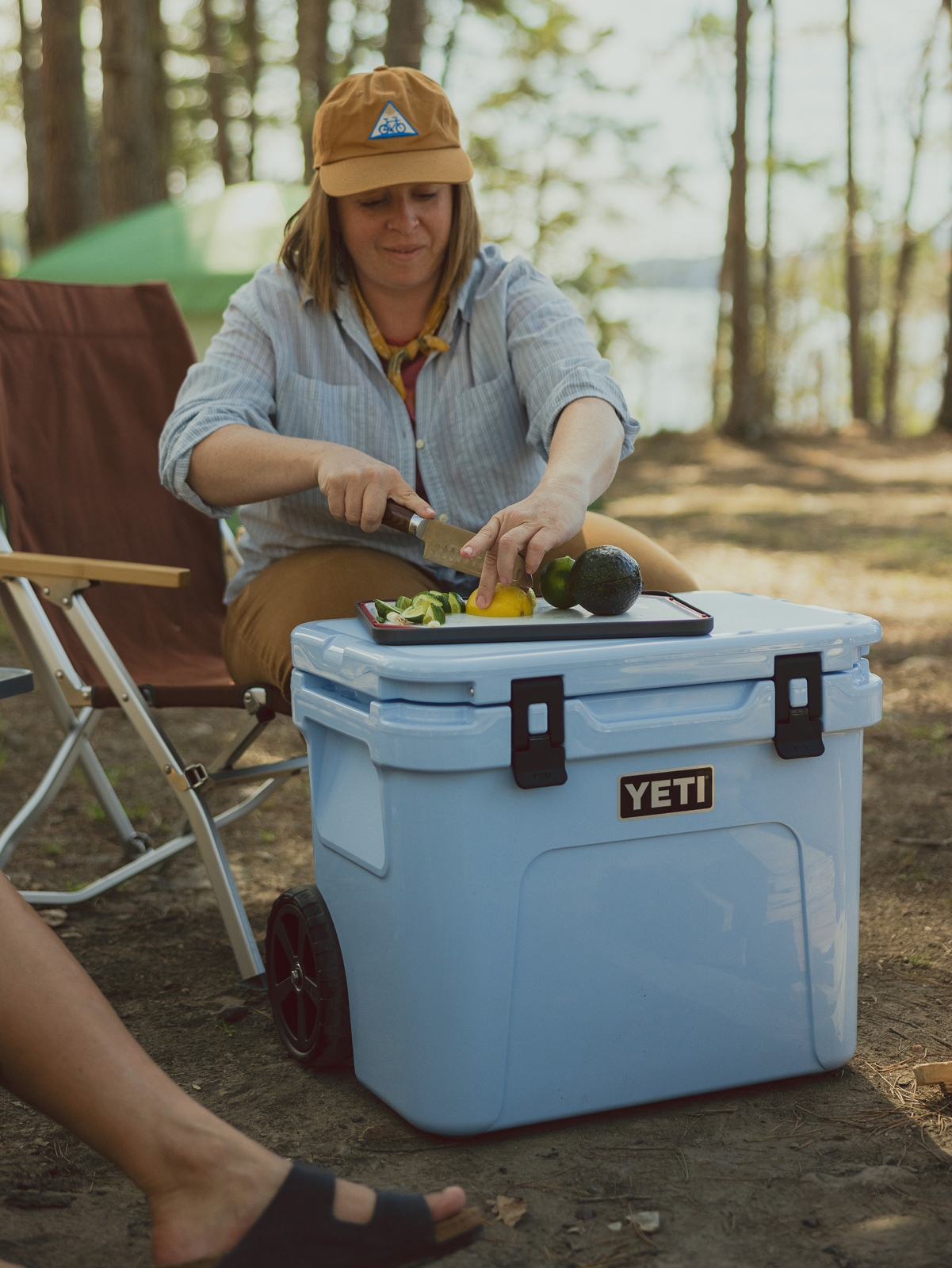 A person slices a lemon on a cutting board on top of their YETI cooler.