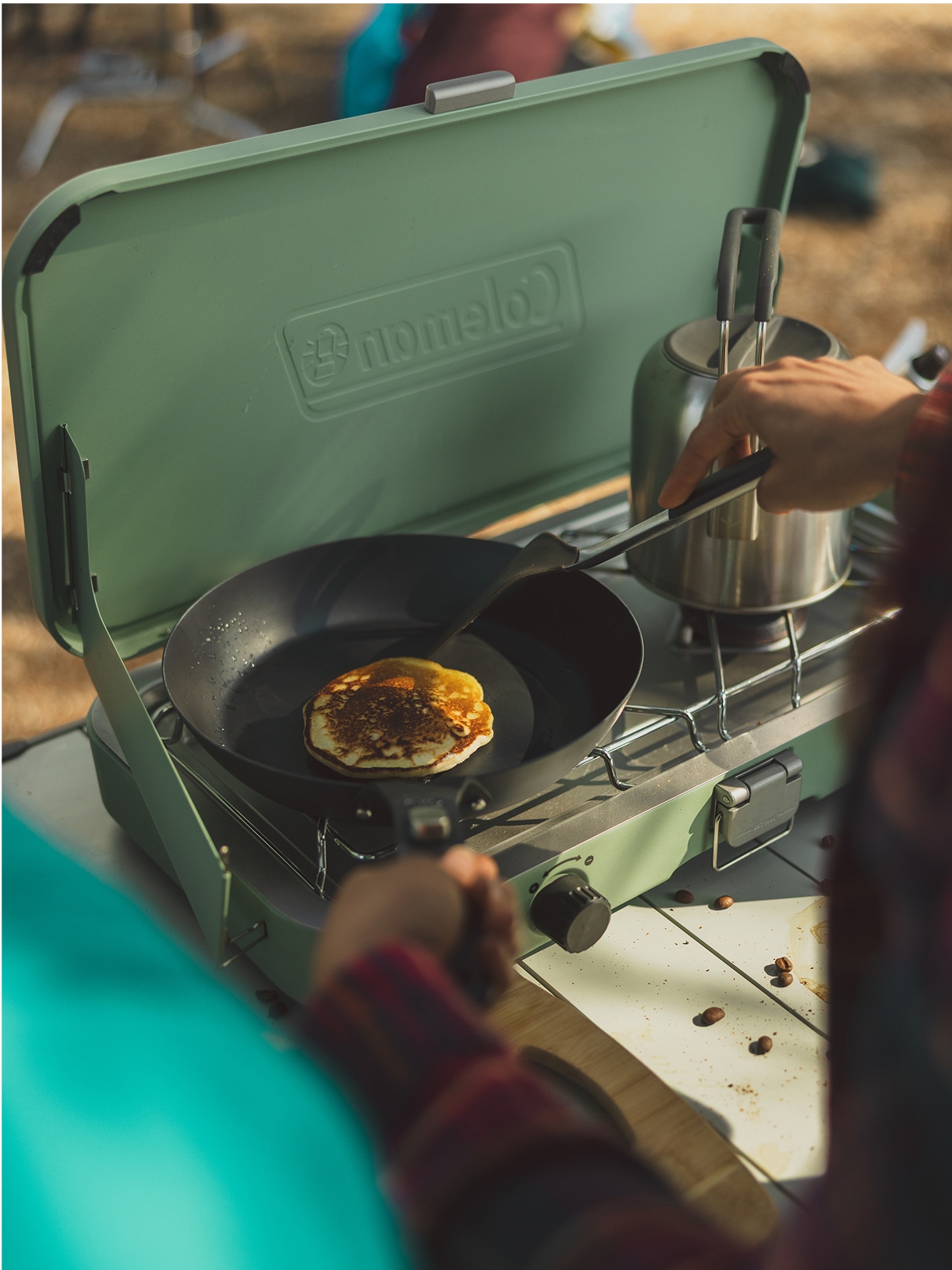 A person makes pancakes on their Coleman camp stove.
