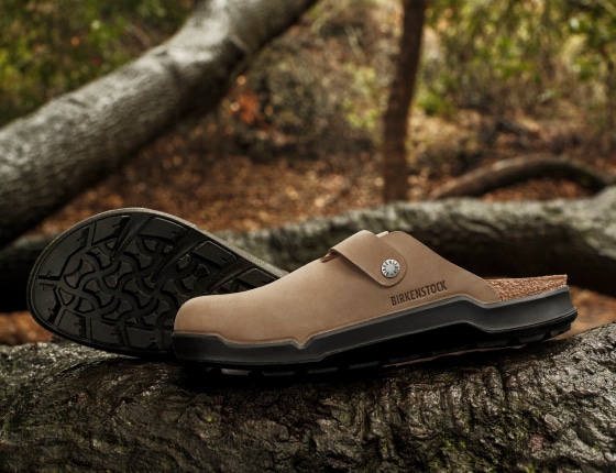 The new Boston Crosstown clogs sitting on top of a tree trunk with a forest in the background.
