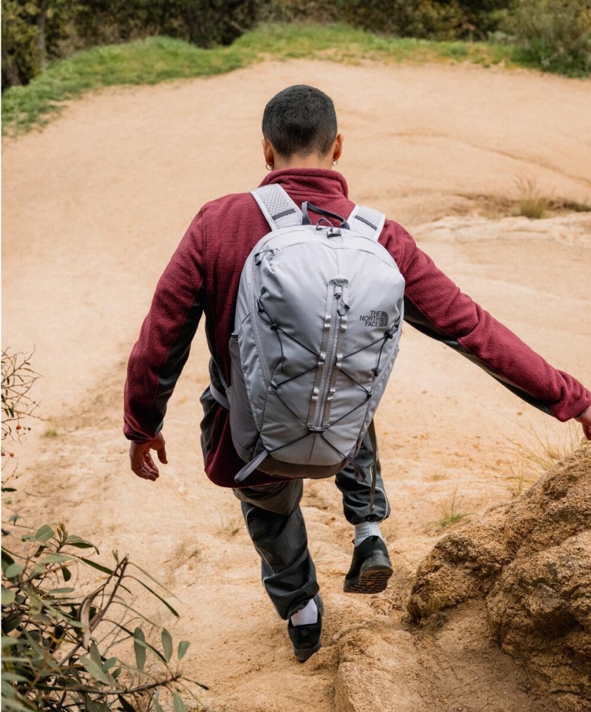 A person hikes down a rocky path with their North Face backpack on.