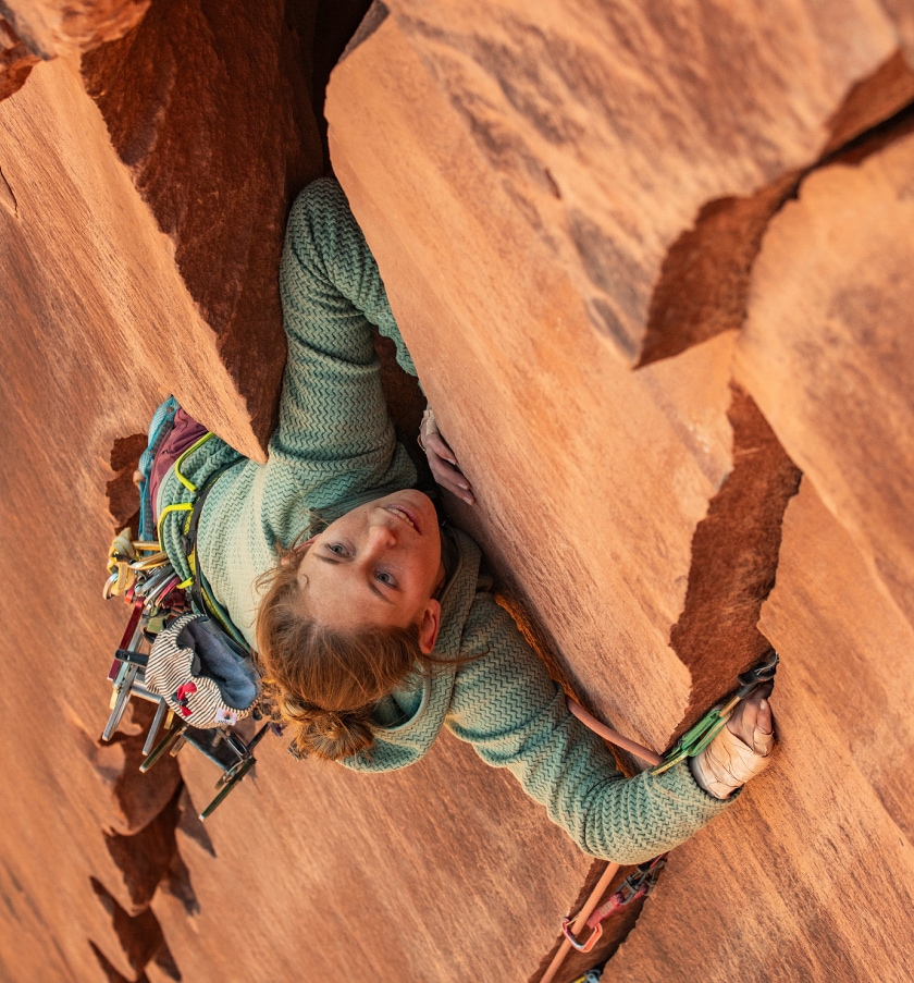 A person climbs up a rock face in their Patagonia R1 Air hoody.