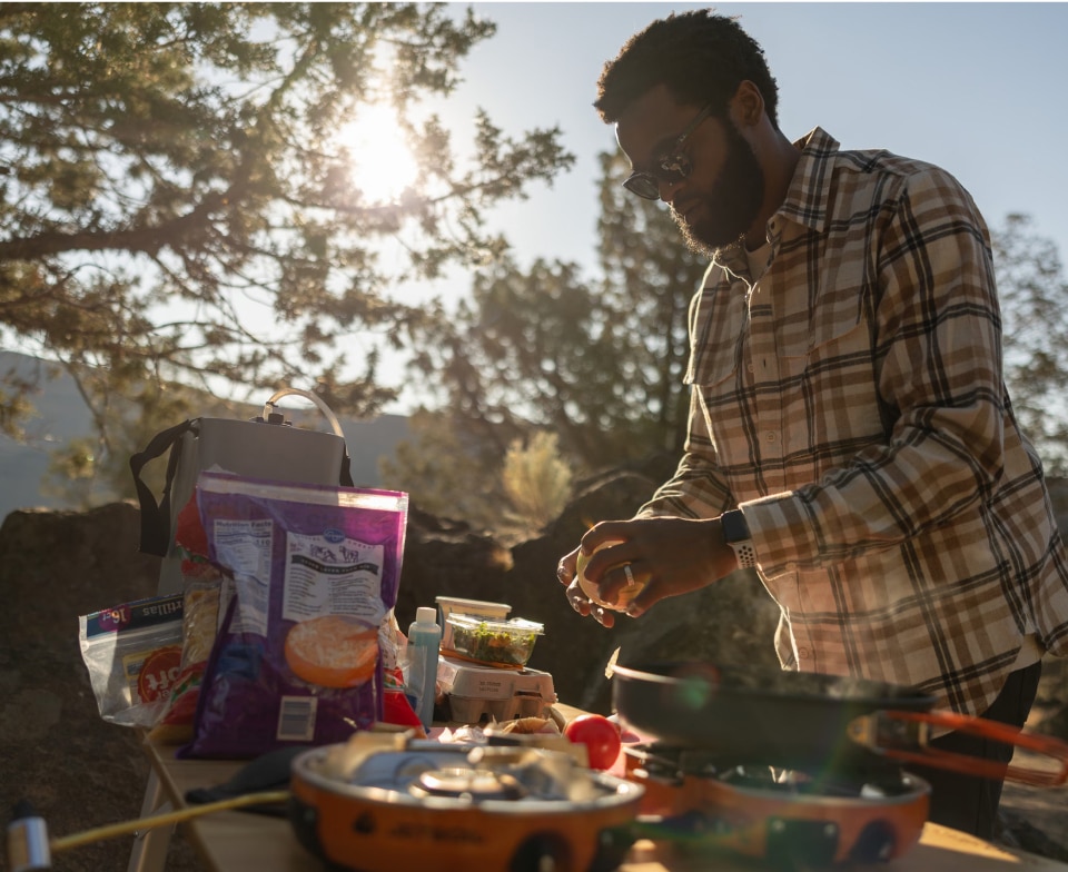 A person holding an onion prepares to make tacos at their campsite.