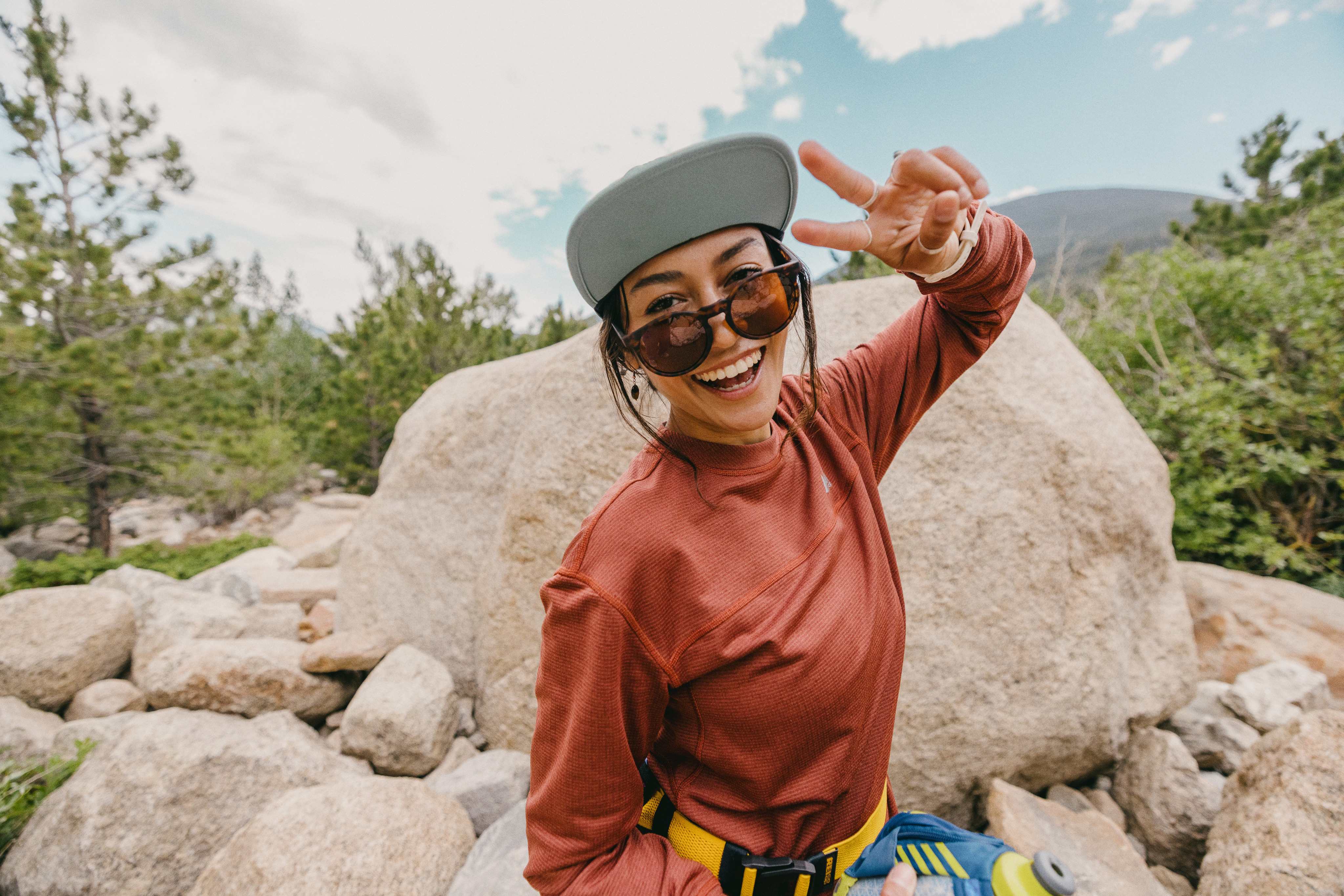 A person throws up a peace sign and smiles for the camera.
