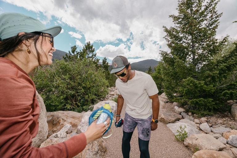A woman and man taking a water break during a trail run.