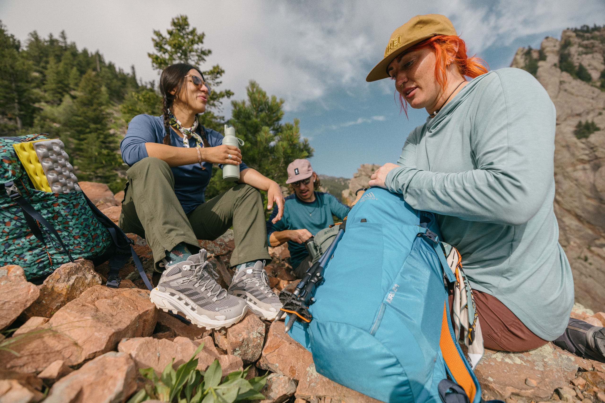 Three hikers wearing hiking clothing take a break during a hike