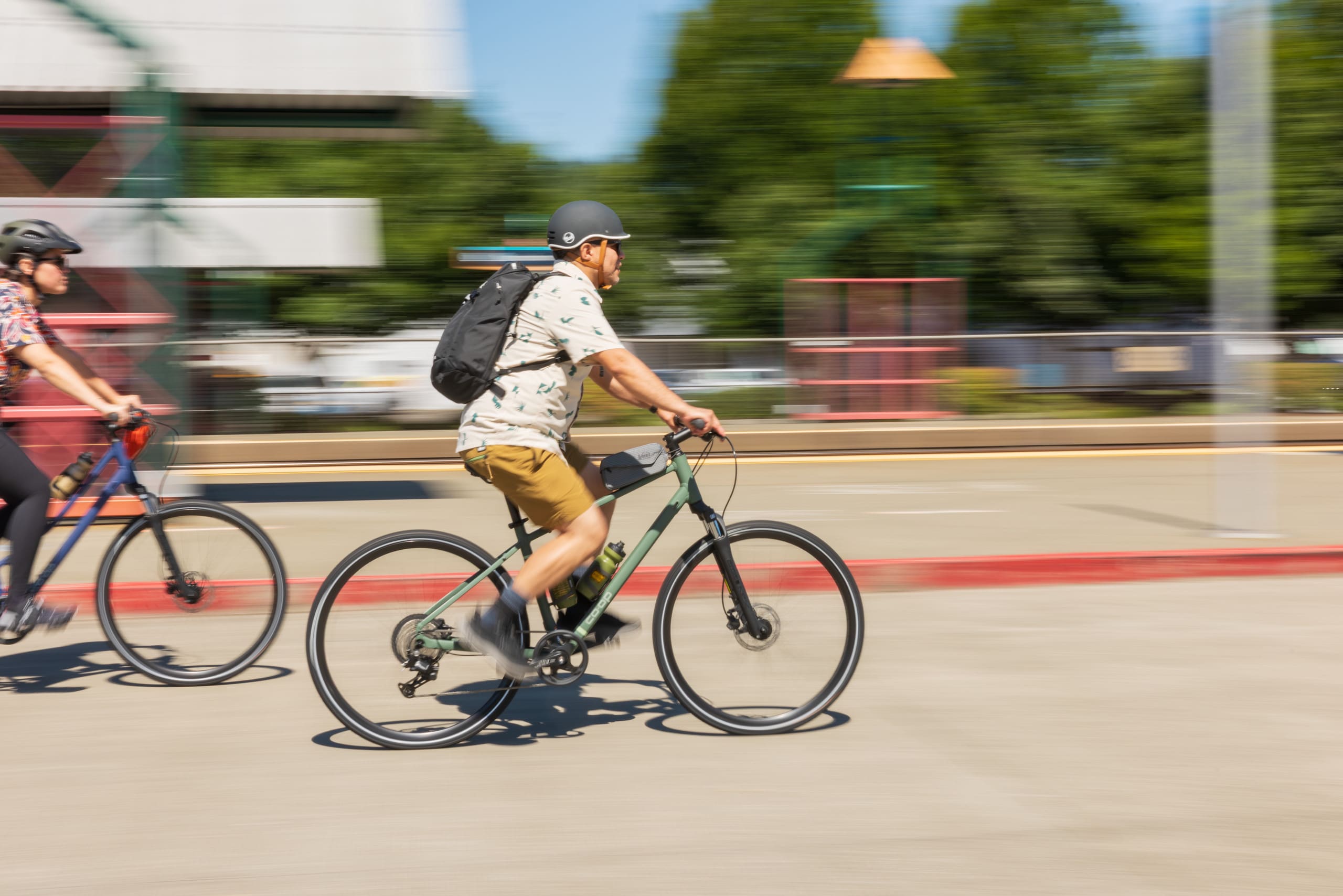 Two cyclist riding Co-op Cycles hybrid bikes around town.