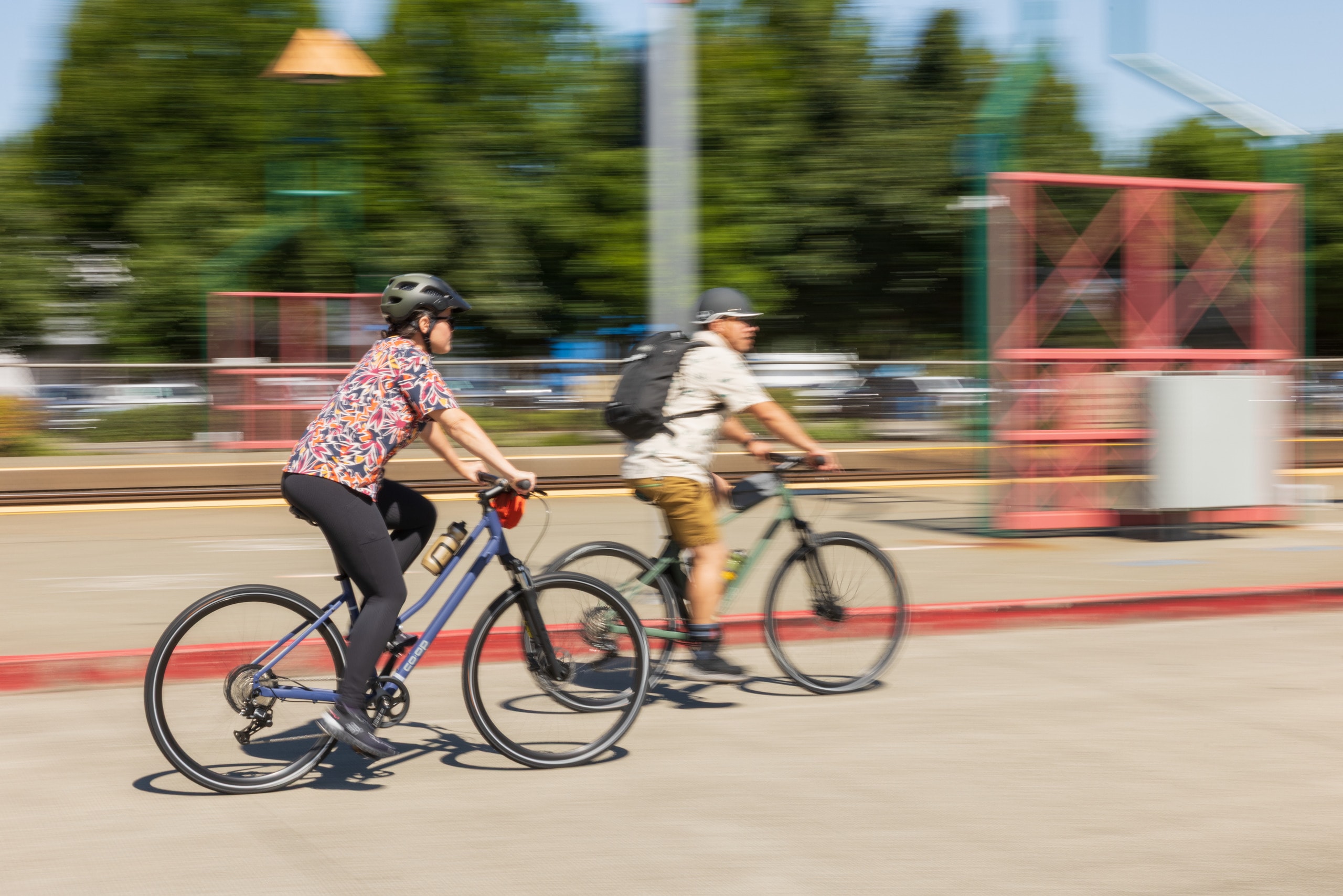 Two people ride bikes through a city